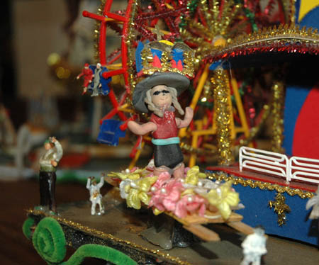 A miniature Robyn wearing a big hat, on her hat